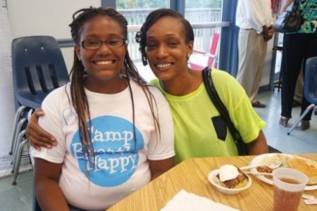 Two women sitting at a table smiling for the camera.