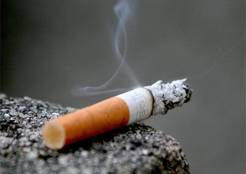 A cigarette is lit up on the side of a rock.